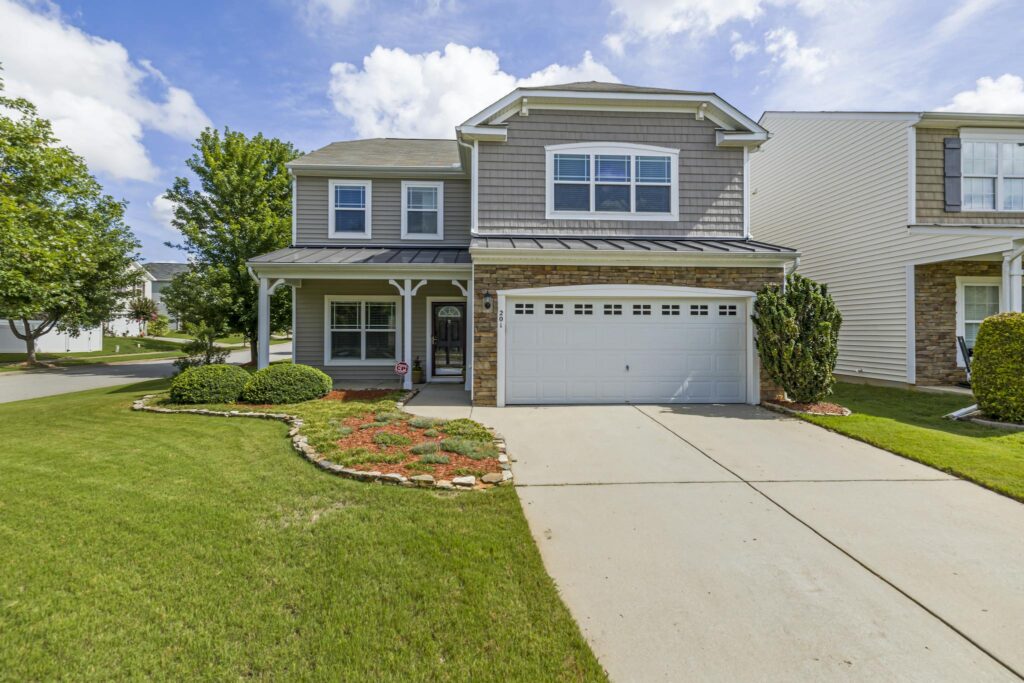 Charming suburban house facade with a tidy front yard, located in a residential neighborhood.
